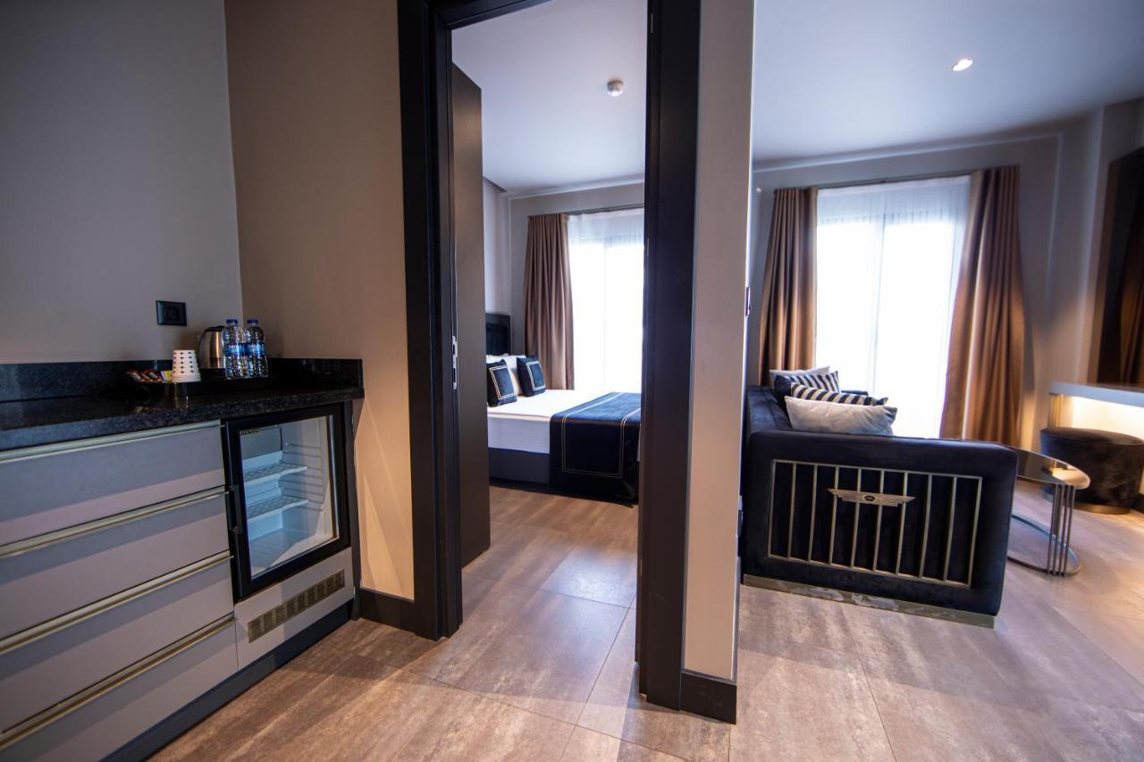 Menalo Hotel Premium Istanbul Airport Exterior foto The photo shows an interior space that appears to be a modern hotel suite or apartment. On the left, there's a small kitchenette area featuring a refrigerator and possibly coffee-making facilities, with a sleek countertop. The entrance leads to a liv