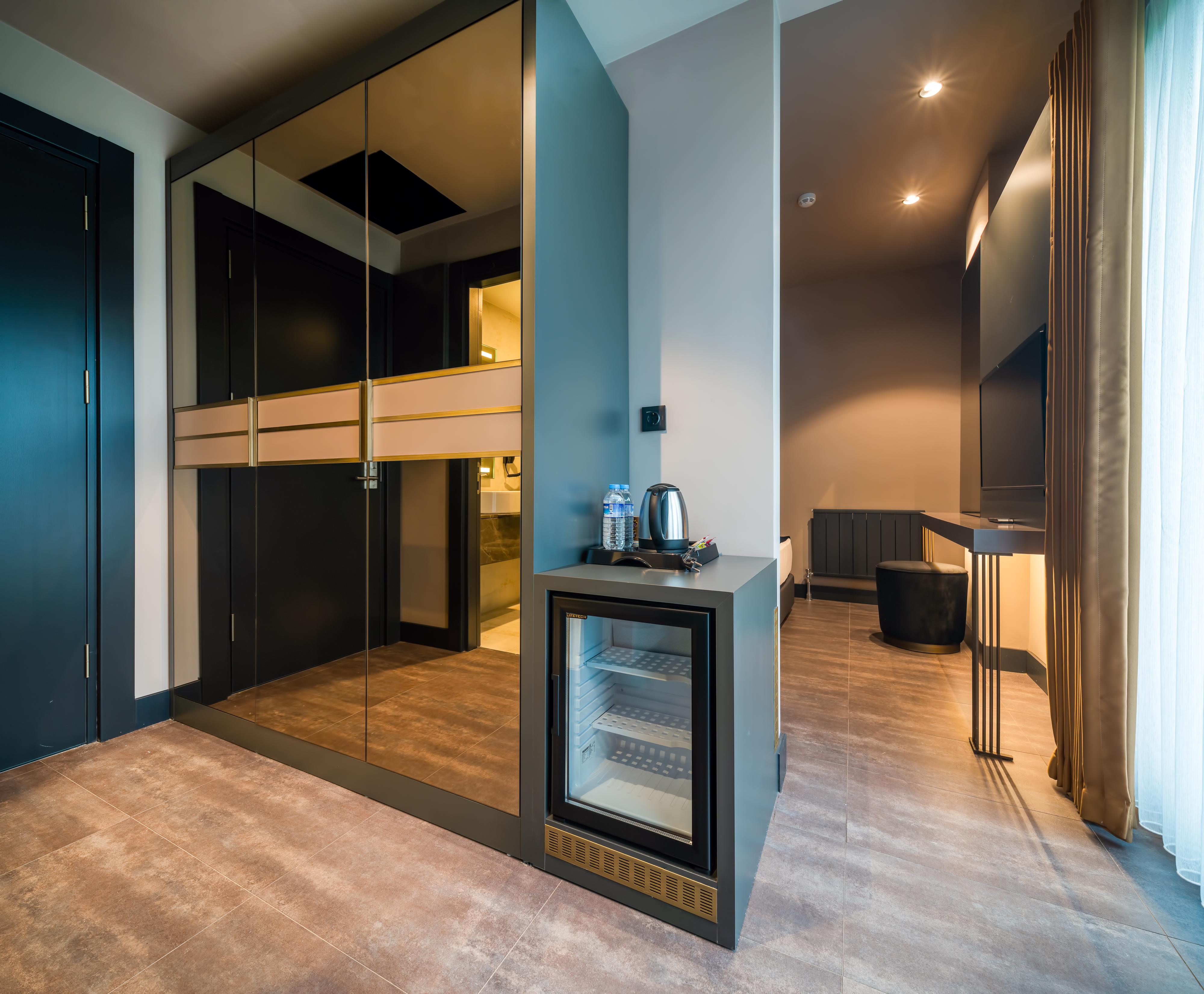 Menalo Hotel Premium Istanbul Airport Exterior foto The photo shows a modern interior space that appears to be part of a hotel room or a high-end apartment. On one side, there is a set of sleek, dark wardrobes with mirrored doors. Next to the wardrobes, there is a small bar area or mini-fridge with a 