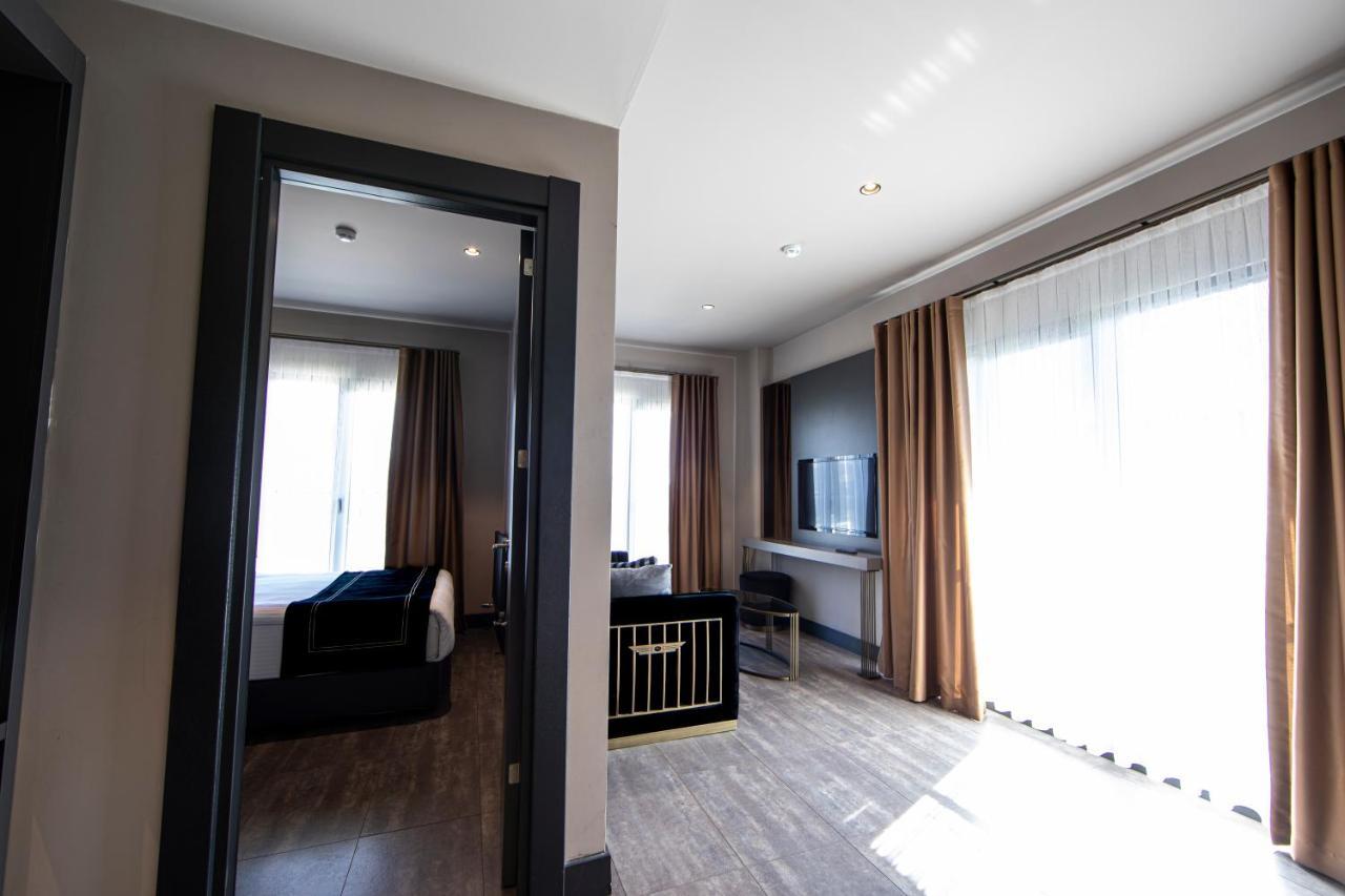 Menalo Hotel Premium Istanbul Airport Exterior foto The photo shows an interior space, likely a hotel room or suite. On the left, there is a doorway leading to another area, and across from it, large windows with light-colored curtains allow natural light to enter the room. 

The room features a cozy 