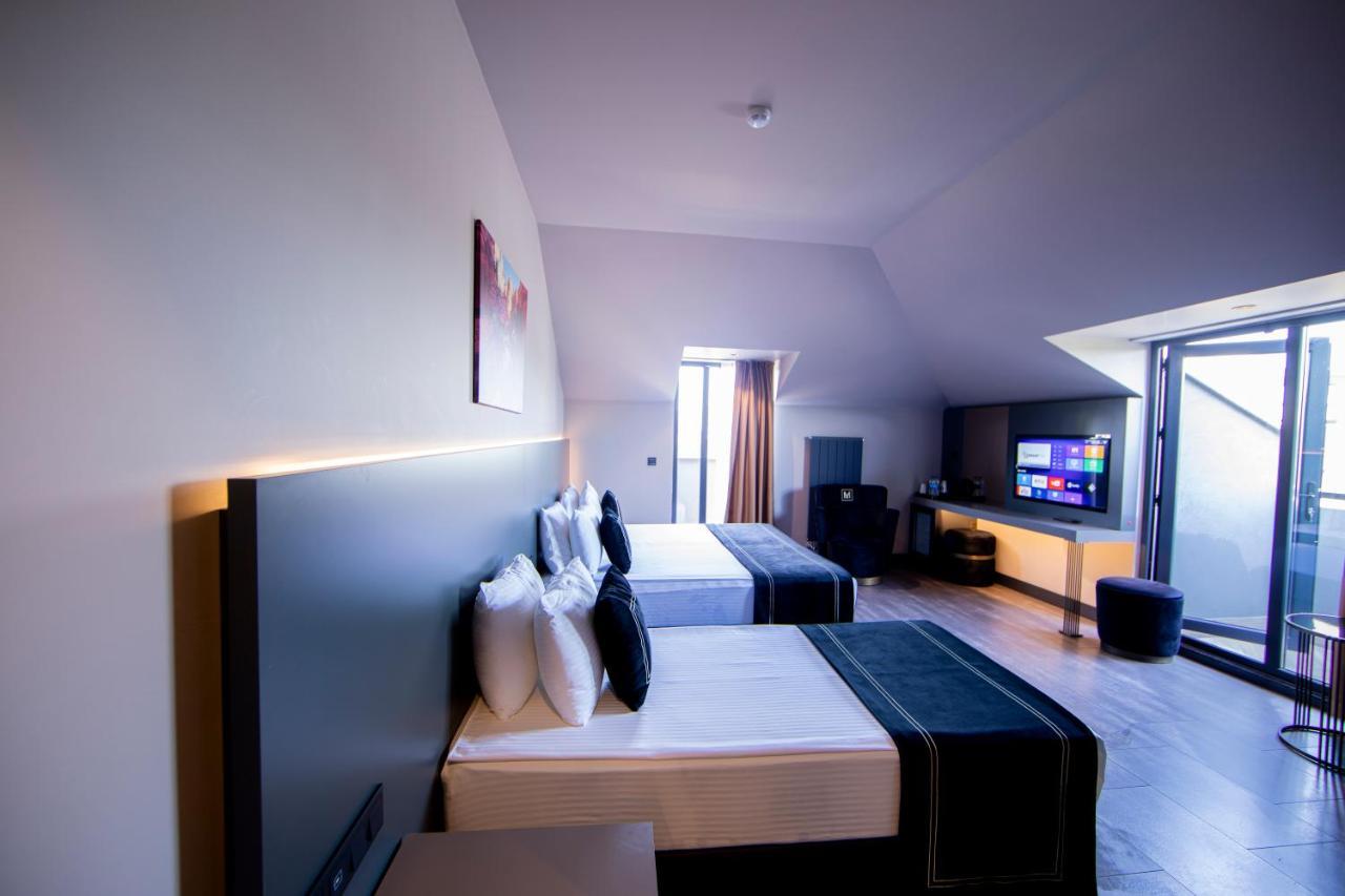 Menalo Hotel Premium Istanbul Airport Exterior foto The photo shows a modern hotel room featuring two beds with stylish black and white bedding. Each bed is adorned with several white pillows. The room has a contemporary design with a light-colored wall and hardwood flooring. There is a large window a